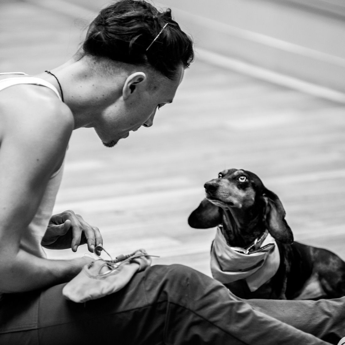 Mateo lacing pointe shoes on the studio floor, a small dog at his side
