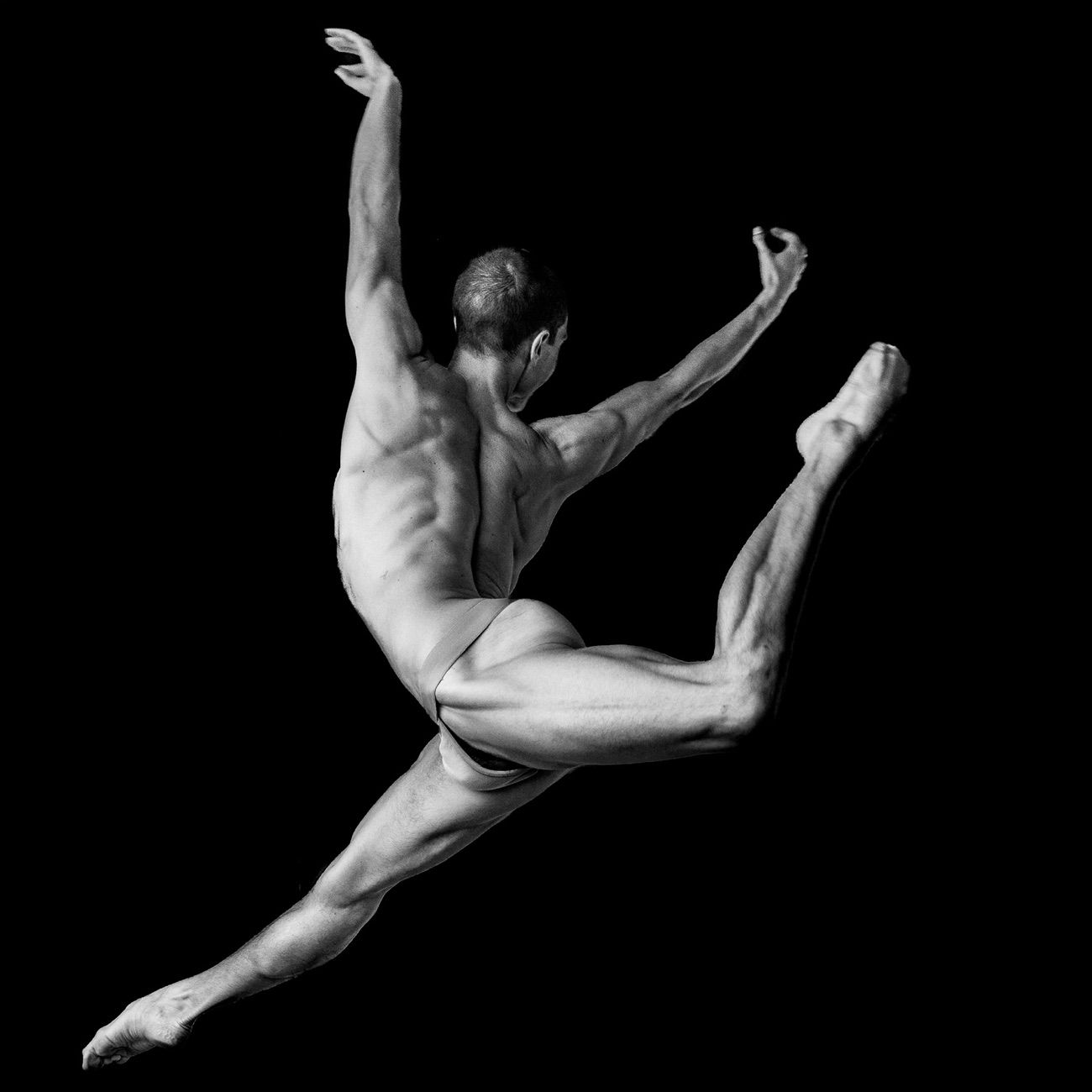 Mateo mid-leap against black, arms and legs extended in a full arc