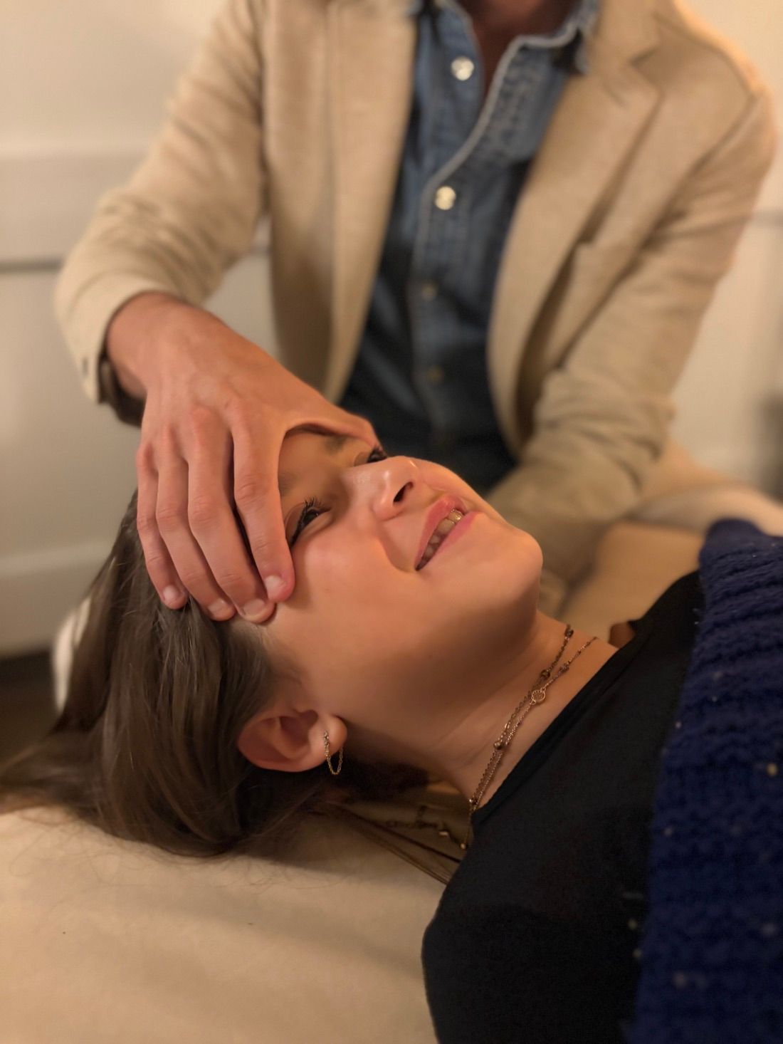 Mateo performing gentle cranial and myofascial work on a smiling client