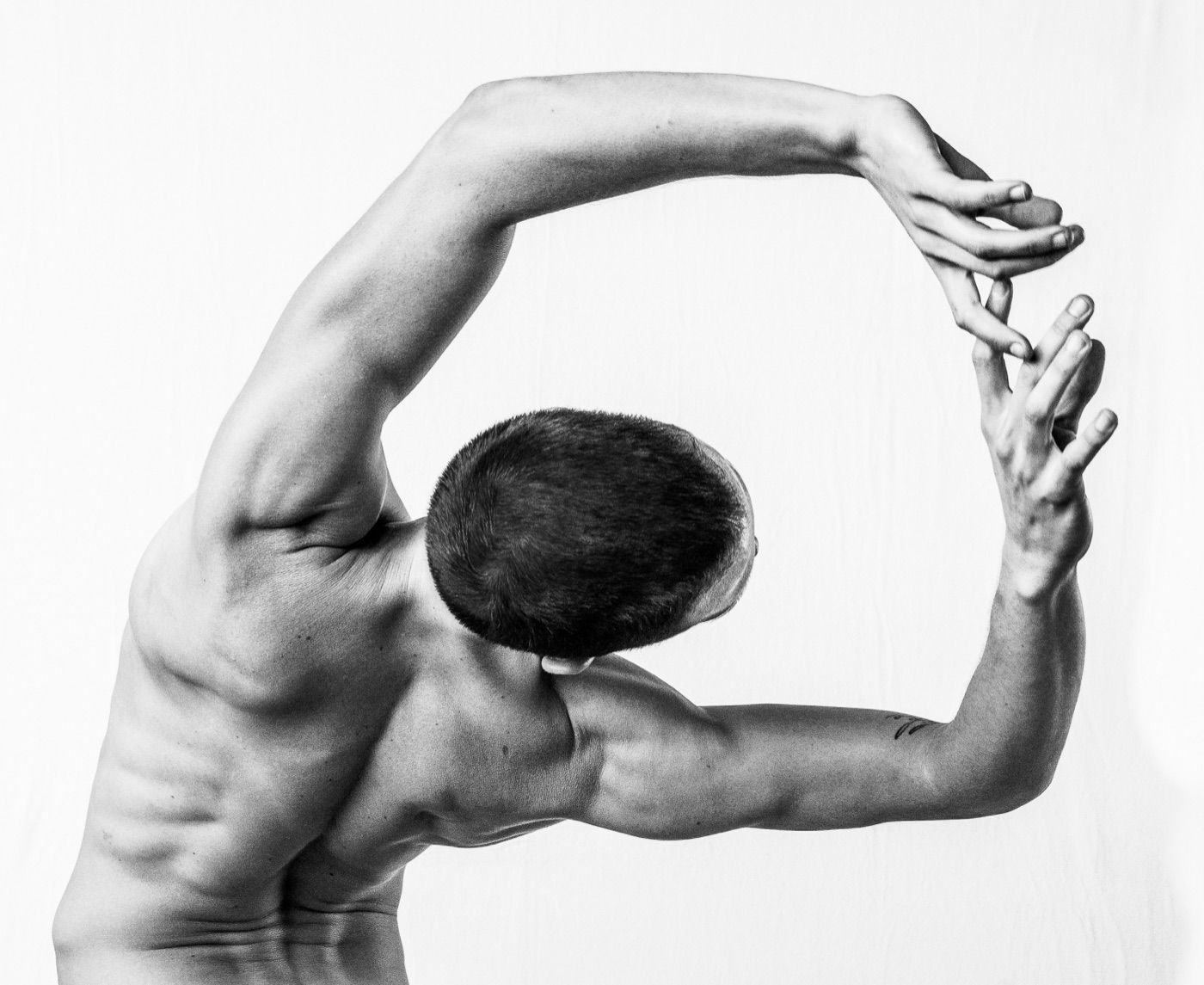 Mateo arcing sideways in a deep stretch, arms curved overhead